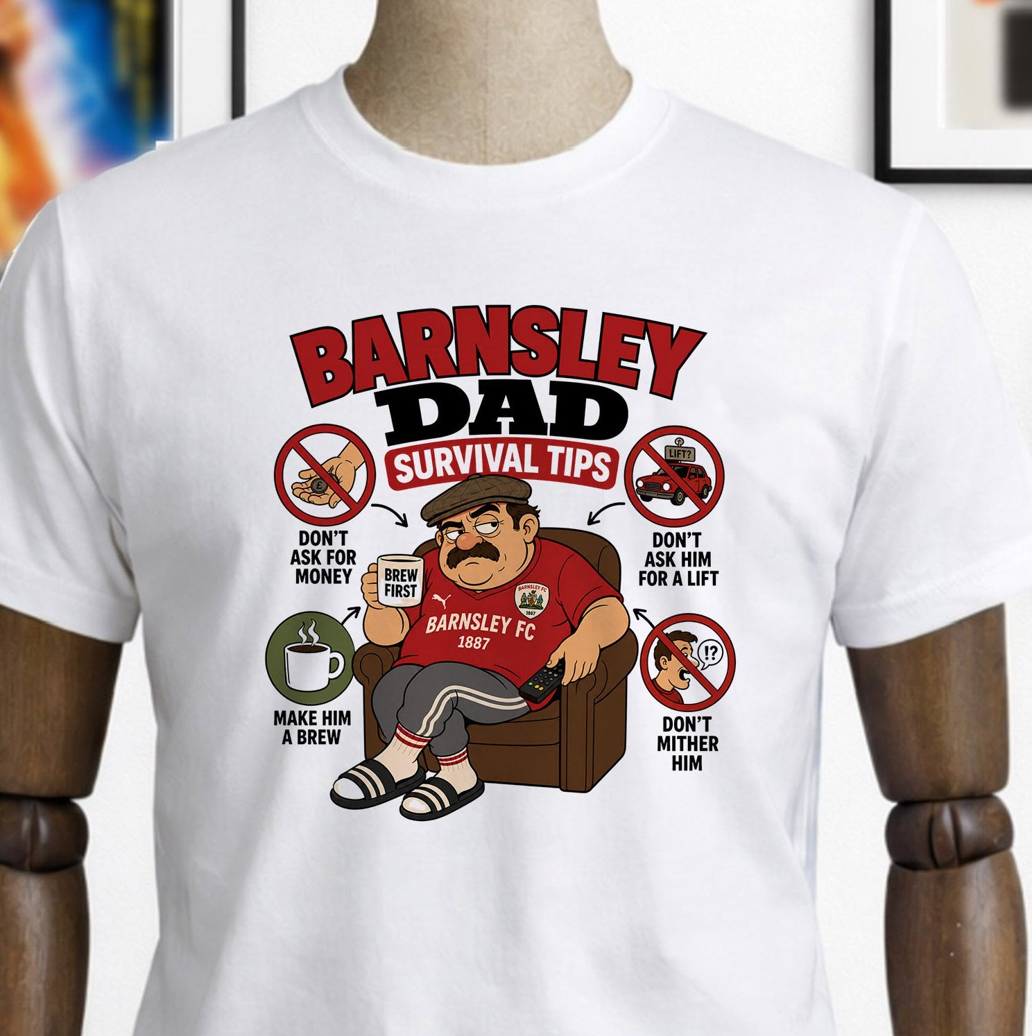 White t-shirt with 'Barnsley Dad' design on a mannequin, with a skateboard and framed pictures in the background.